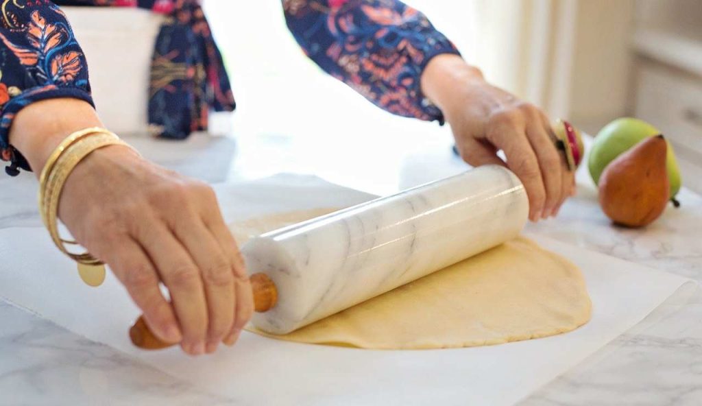 Stendere la pasta con mattarello su carta forno