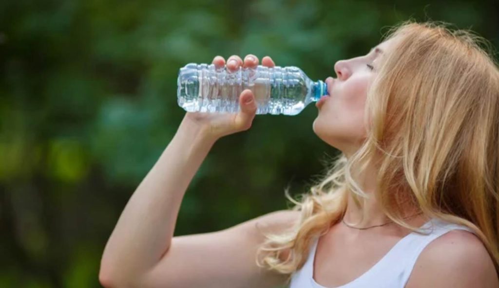 Donna beve dell'acqua da una bottiglietta