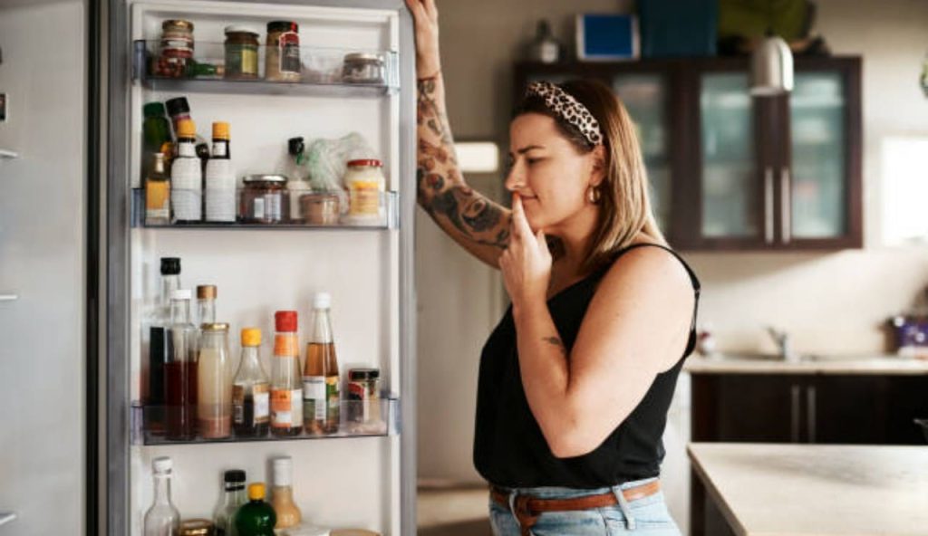 Ragazza guarda davanti al frigo aperto